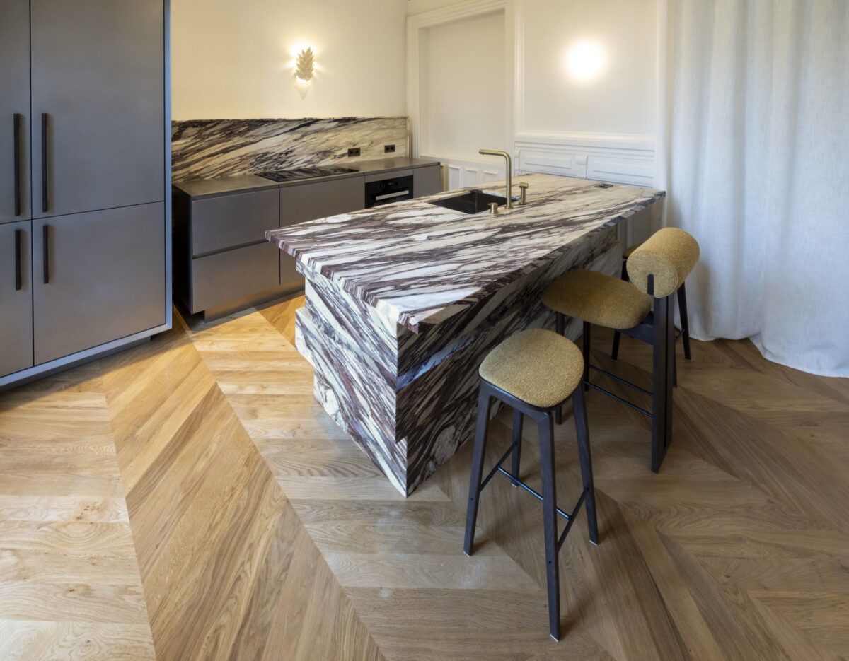Îlot de cuisine en marbre Calacatta aux veines pourpres avec tabourets en cuir, parquet en chevrons