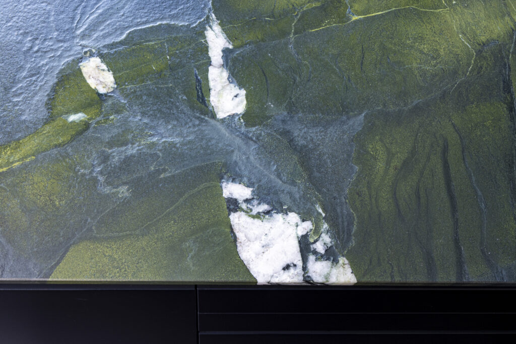 Gros plan sur une pierre naturelle aux veines vertes, grises et blanches dessinant un mouvement sinueux