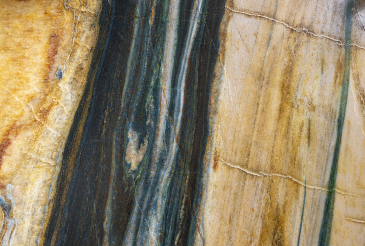 Gros plan sur une pierre naturelle aux veines ocre, bleu marine et blanches