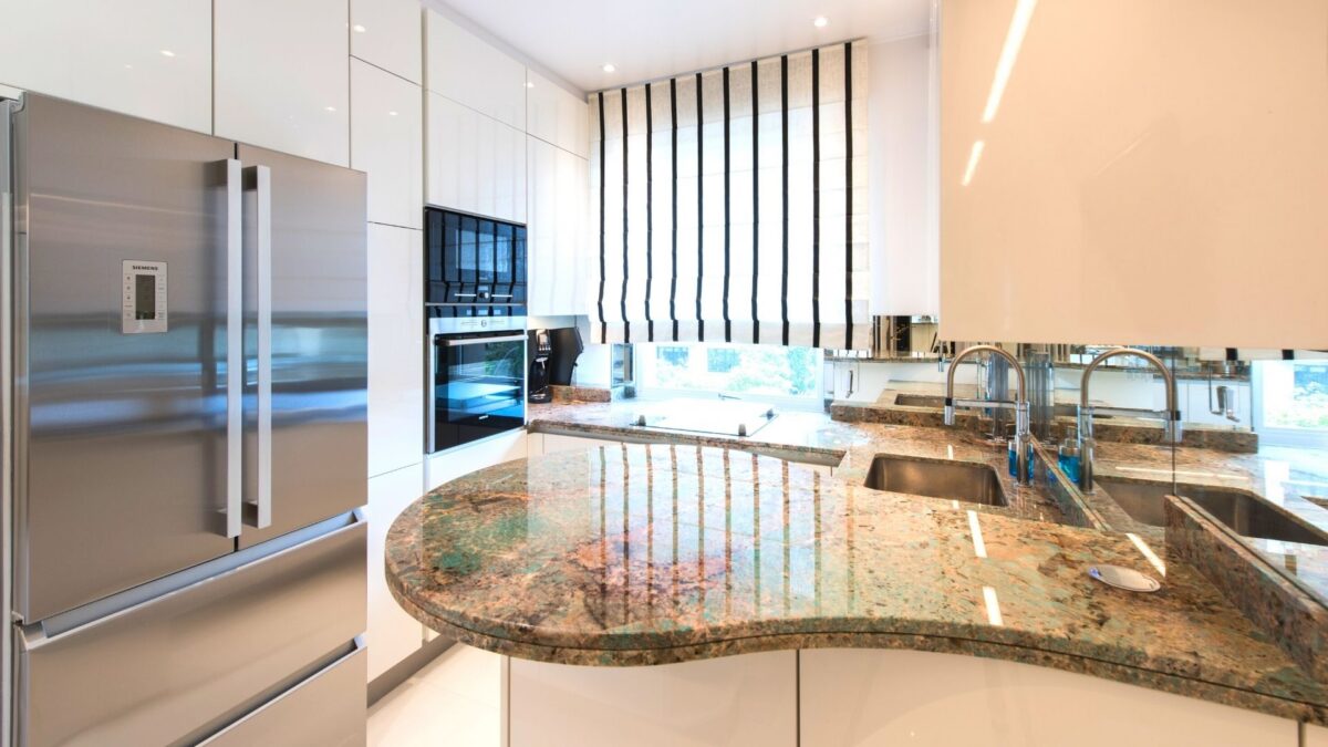 Îlot de cuisine arrondi en granit vert et doré avec réfrigérateur inox et éclairage design