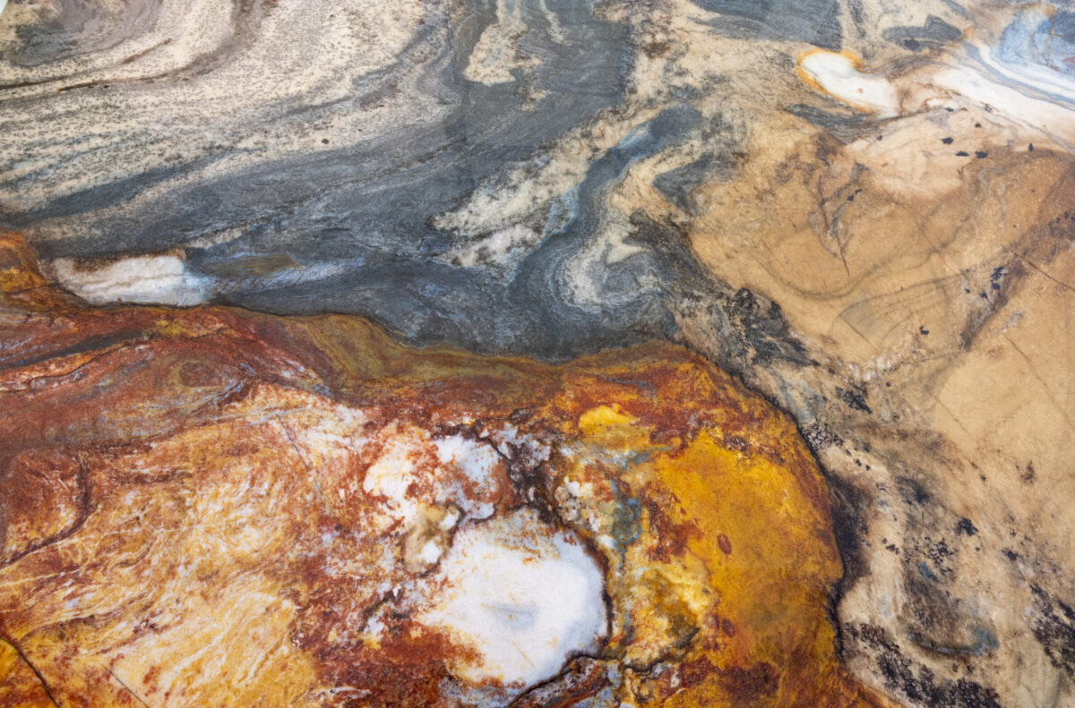 Gros plan sur une tranche de quartzite aux veines orange, bleues et grises