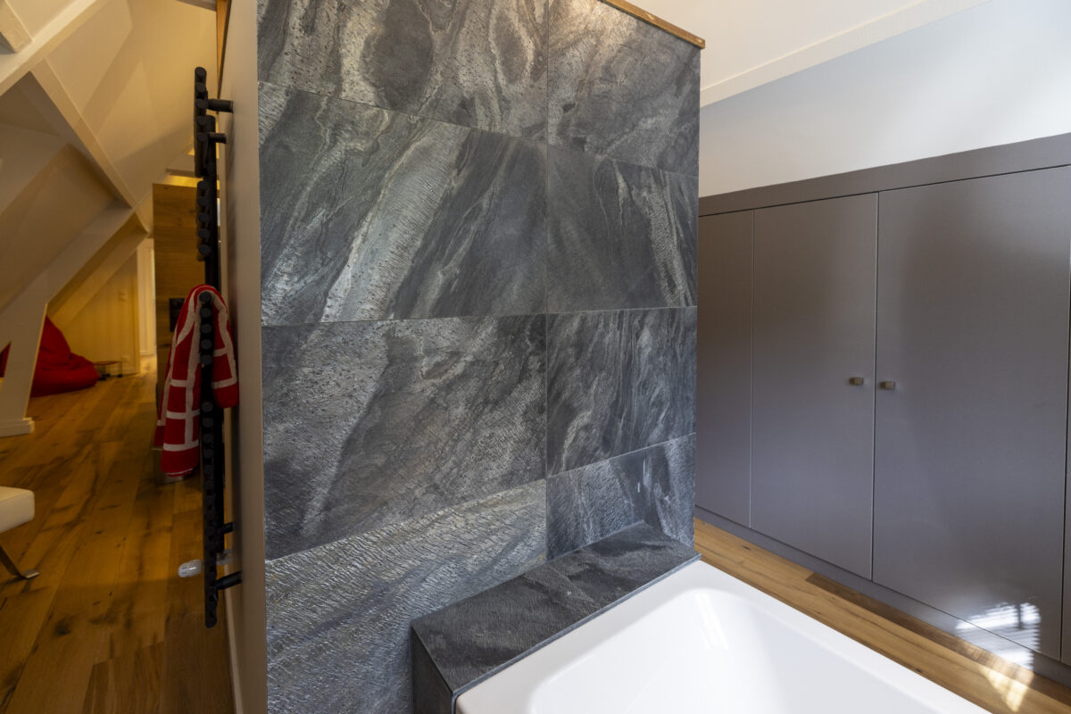 Mur de salle de bain en pierre grise texturée à côté d’une baignoire