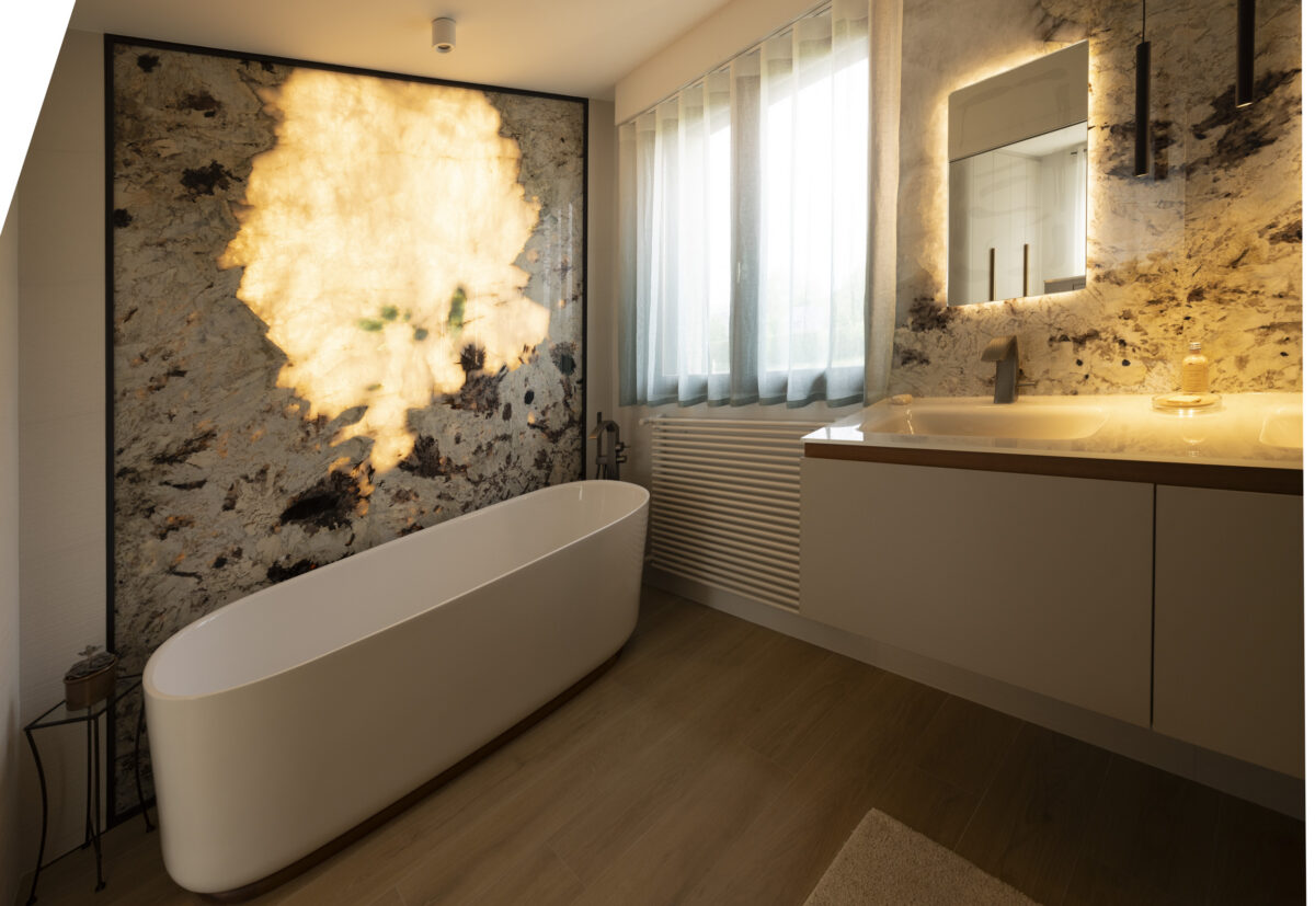 Baignoire îlot devant un mur en pierre translucide rétroéclairée