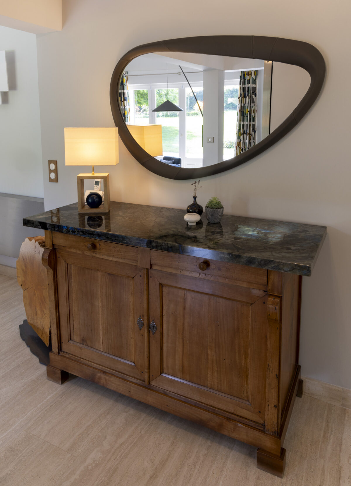 Buffet en bois ancien à plateau en pierre sombre sous un miroir ovale