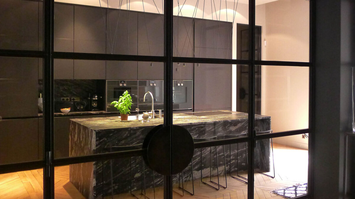 Îlot de cuisine en granit noir verdâtre dans une cuisine ouverte avec grande baie vitrée