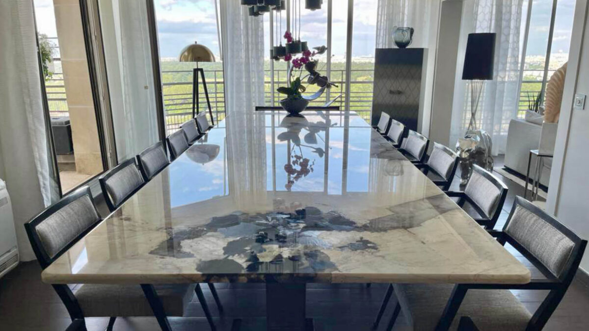 Grande table en granit Patagonia entourée de chaises noires face à une baie vitrée