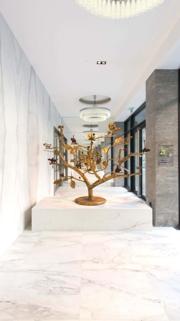 Grand hall intérieur en marbre clair avec une sculpture dorée posée sur un socle