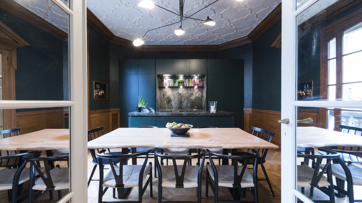 Salle à manger avec table en bois et cuisine en labradorite sur un sol en lames