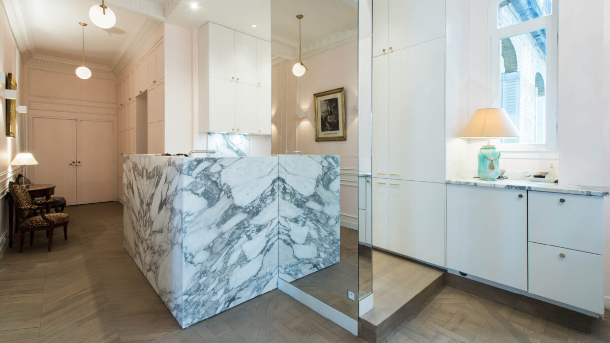 Meuble d’entrée habillé de marbre blanc veiné, parquet chevron
