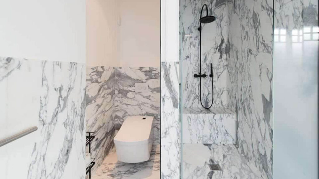 Marbre blanc veiné de gris sur le sol et les murs d'une salle de bain lumineuse