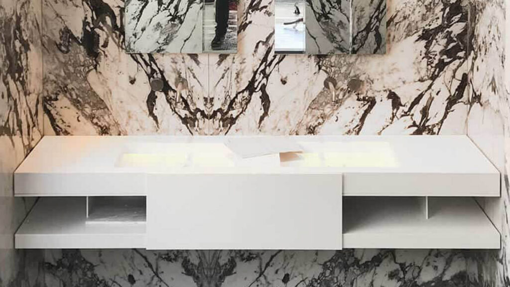 Double vasque intégrée à un plan de marbre veiné de vert et de noir sur un meuble suspendu blanc
