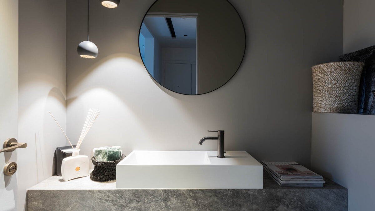 Plan vasque en pierre grise sous un miroir rond