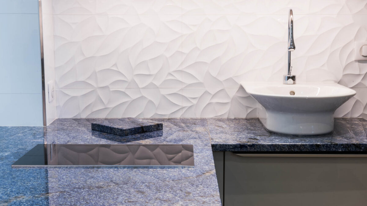 Plan de cuisine en granit Azul Bahia bleu avec vasque blanche devant un mur en relief