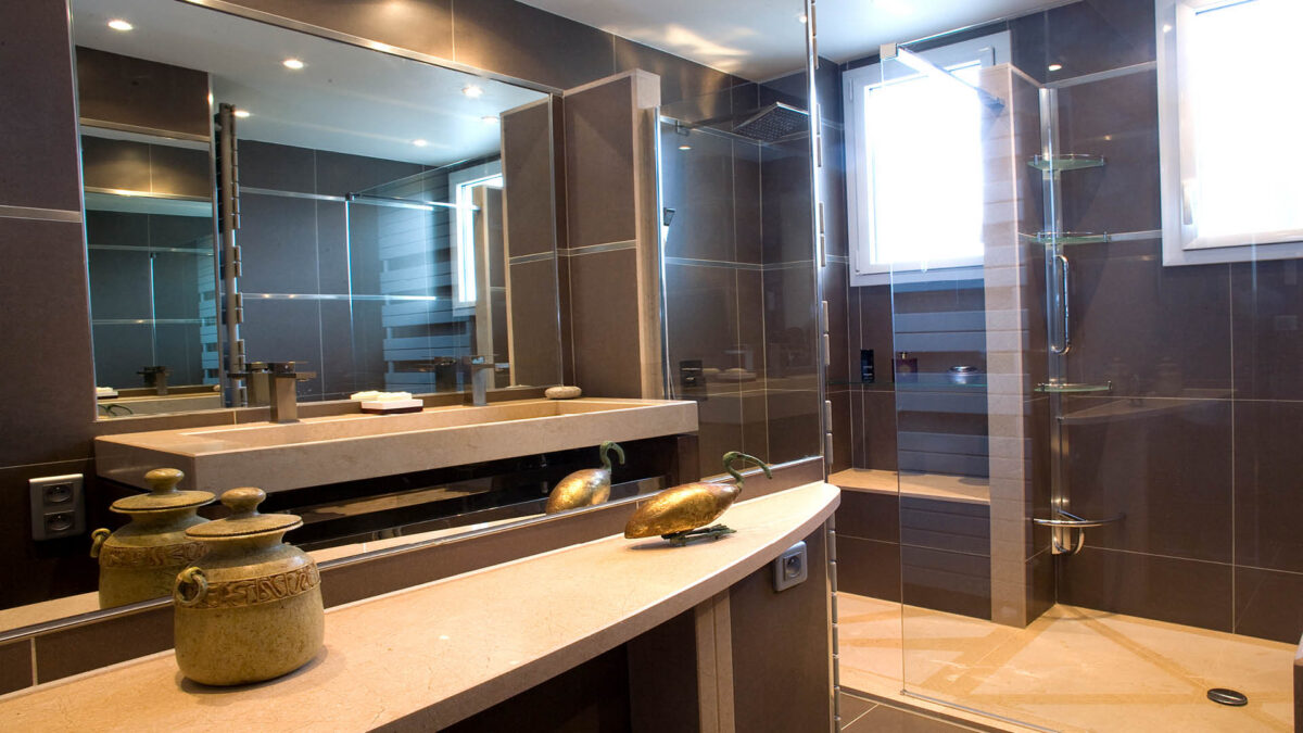 Double vasque et plan en marbre cognac doré sous des miroirs lumineux