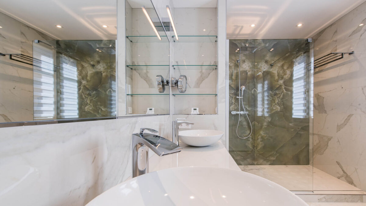 Salle de bains en marbre blanc avec vasque, mitigeur chromé et douche à parois de verre
