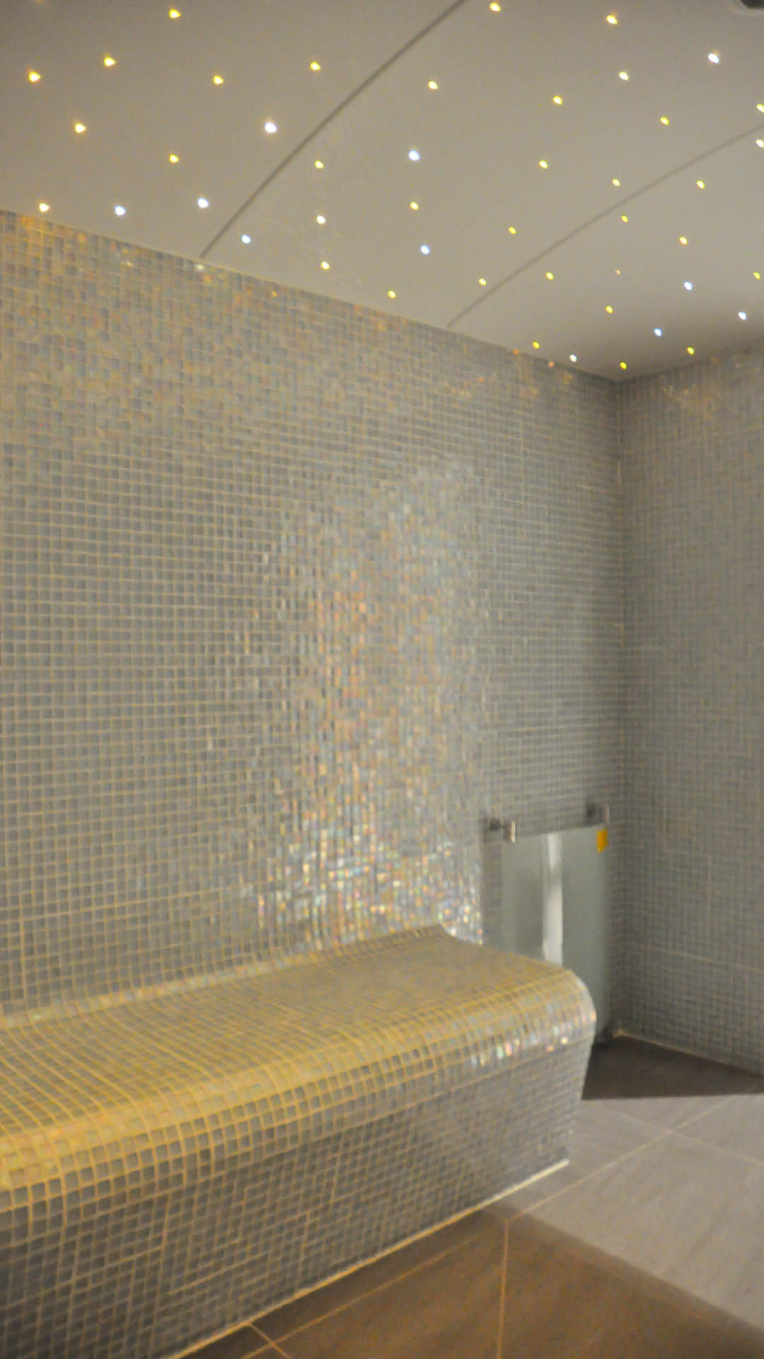 Banquette et murs en mosaïque nacrée dans un spa à plafond étoilé