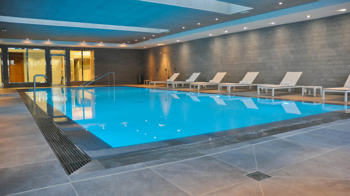 Piscine intérieure du spa Nuxe bordée de margelles et d'une plage en pierre grise