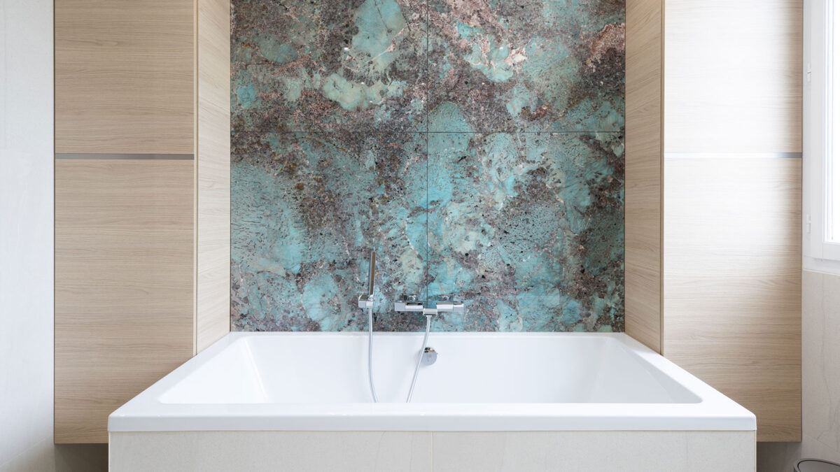 Baignoire blanche adossée à un panneau mural en amazonite turquoise veinée de brun
