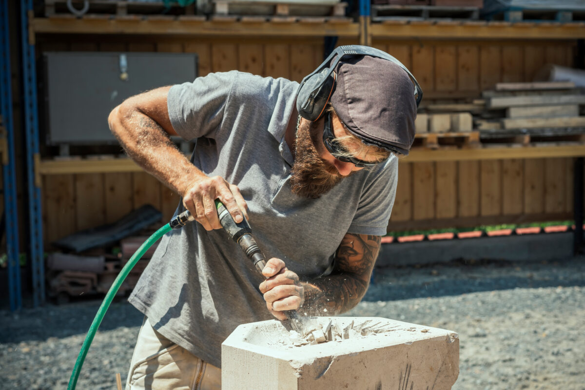 Artisan marbrier taillant un bloc de pierre à l'atelier
