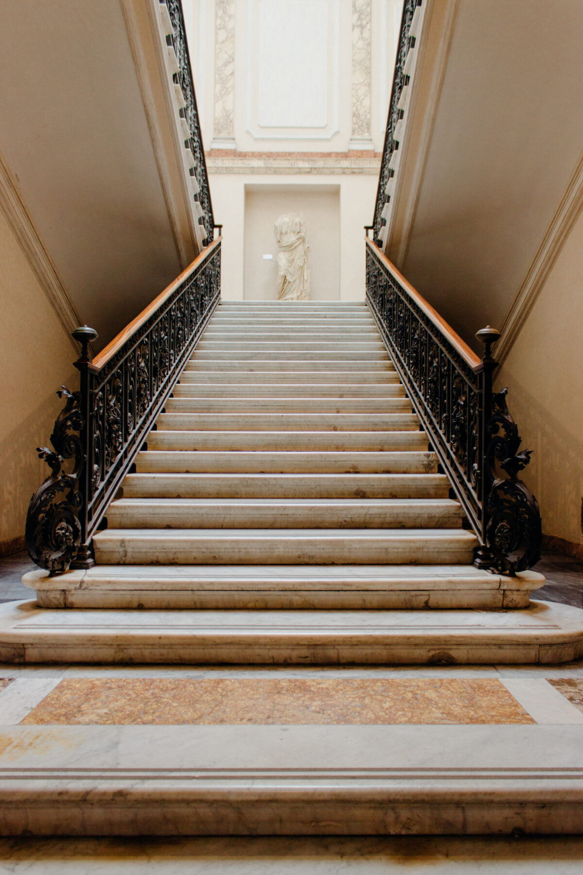 Escalier d'apparat en pierre claire avec rampe en fer forgé