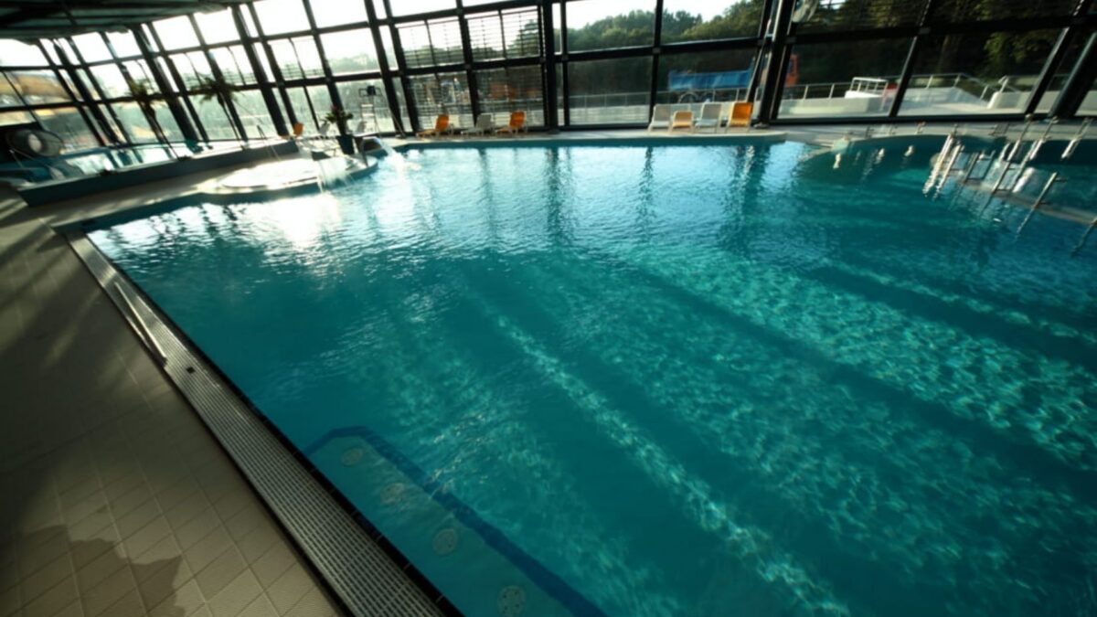 Grand bassin intérieur du centre aquatique de Quimperlé bordé de céramique claire sous une verrière