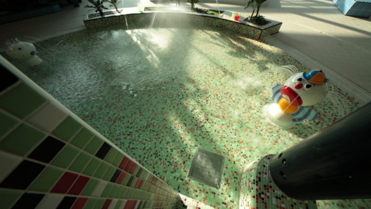 Bassin d'un centre aquatique tapissé de mosaïque verte et rouge