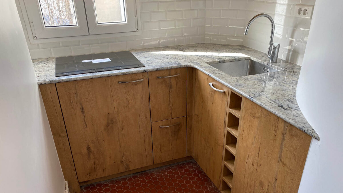 Cuisine aux meubles clairs avec plan de travail en granit gris moucheté