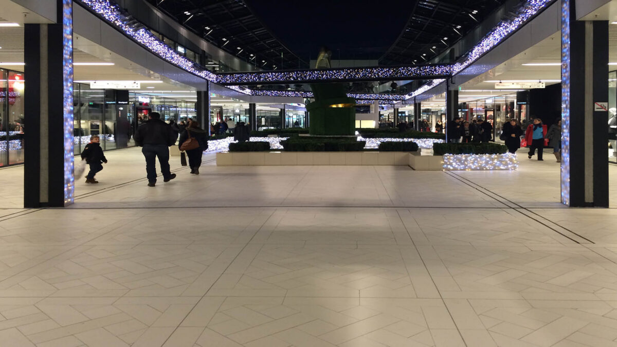 Dalles de grès cérame grand format gris clair au sol d'une galerie commerciale