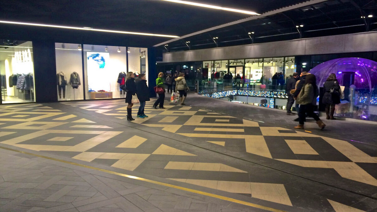 Sol en grès cérame grand format à motifs géométriques noirs et beiges dans une galerie du centre commercial One Nation