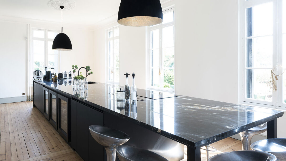 Grand îlot noir avec plan de travail en quartzite Black Fusion veiné de blanc, tabourets en aluminium et suspensions noires