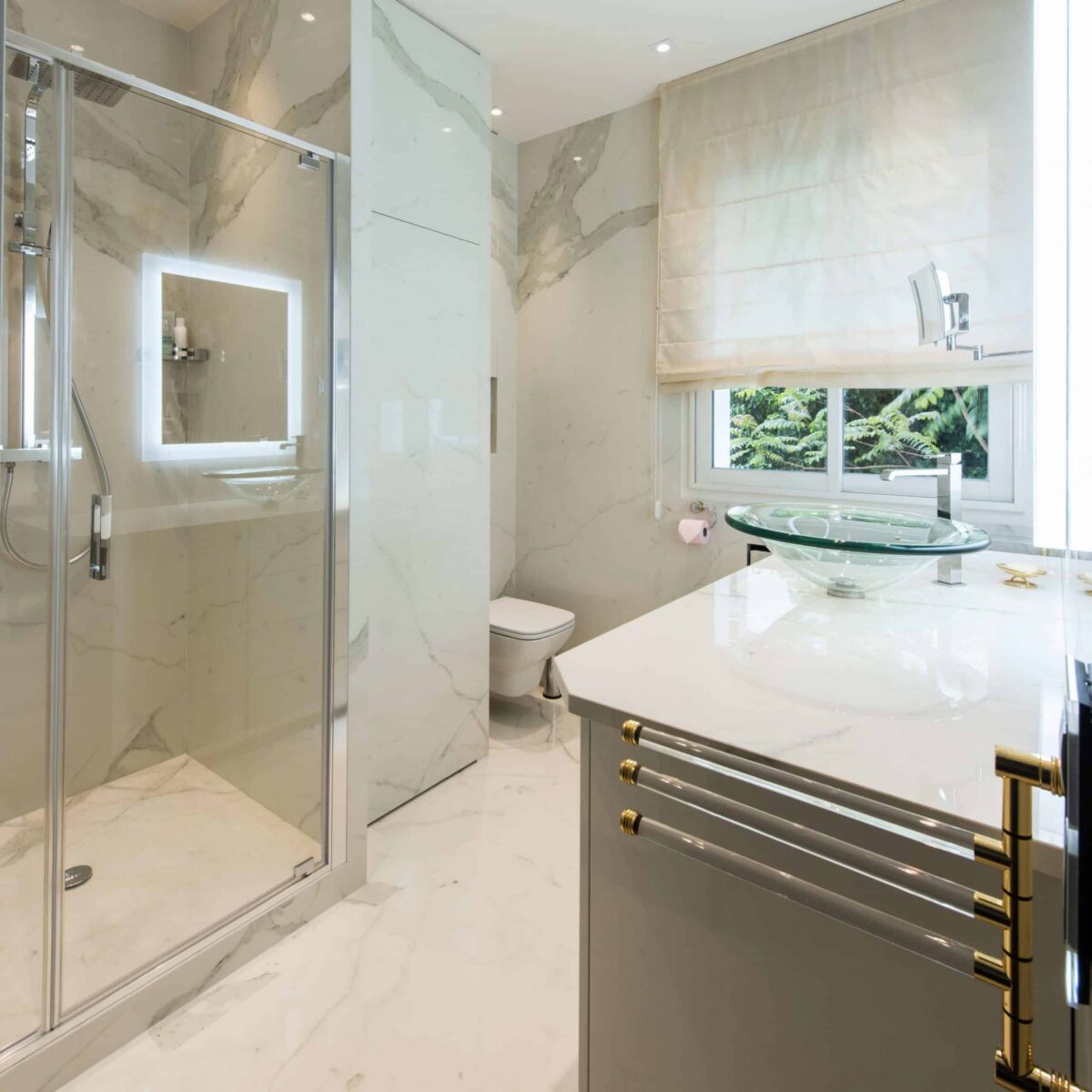Salle de bain en céramique effet marbre blanc veiné, douche vitrée et meuble vasque avec plan clair