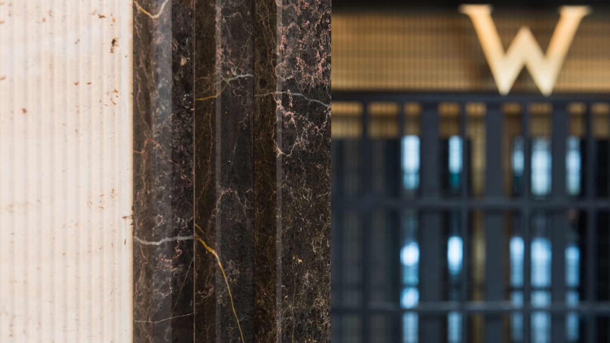 Pilier en travertin cannelé beige associé à un marbre brun veiné dans le hall d'un hôtel