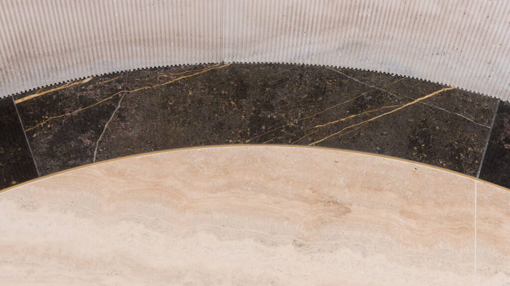 Rebord incurvé en pierre naturelle beige aux nuances fauves, à la surface légèrement texturée
