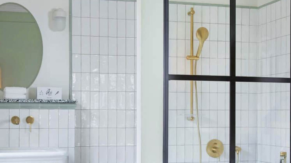 Salle de bains habillée de zelliges blancs avec robinetterie dorée et paroi noire