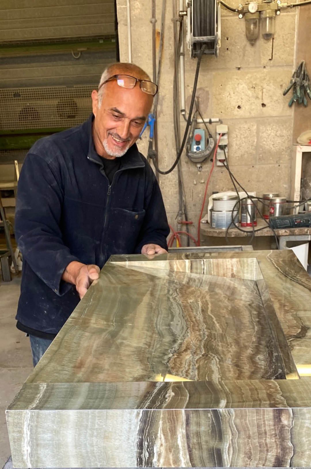 Marbrier MDY à l'atelier, la main posée sur un plan en onyx veiné poli