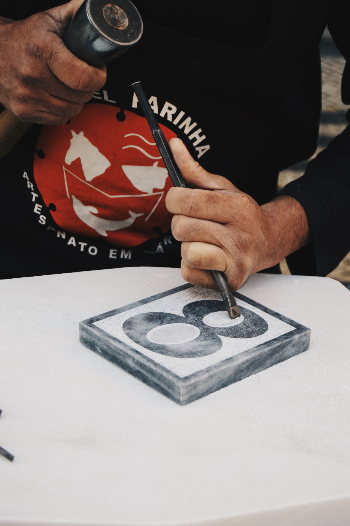 Mains d'artisan sculptant un motif dans une plaque de marbre blanc