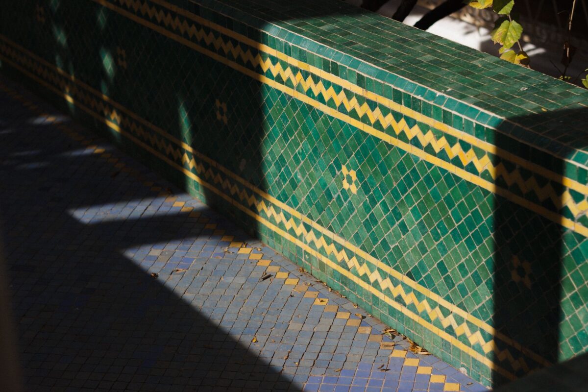 Banc habillé de petits zelliges verts à liseré jaune sous le soleil