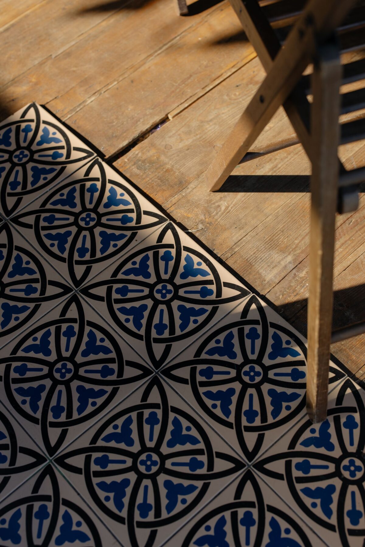 Sol en carreaux de ciment à motif bleu et blanc au bord d'un parquet en bois