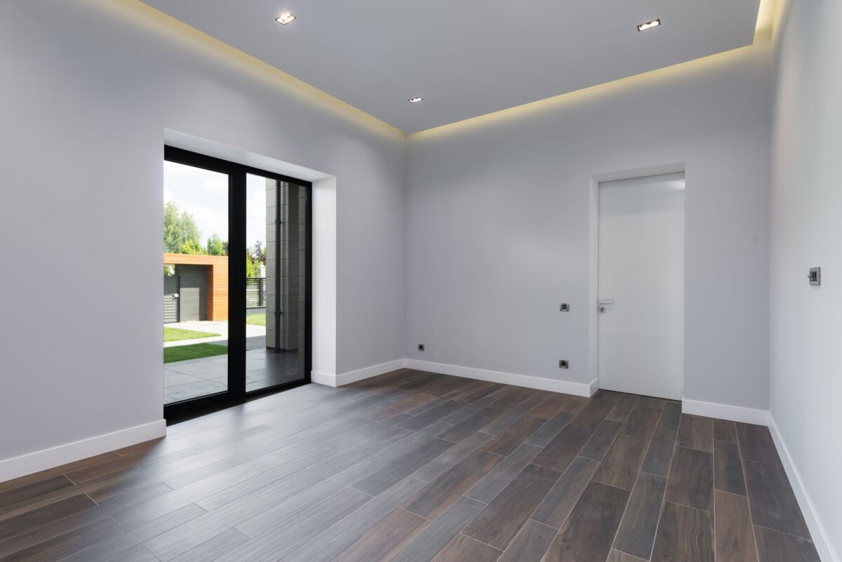 Chambre vide et lumineuse avec sol en carrelage imitation parquet et grandes fenêtres