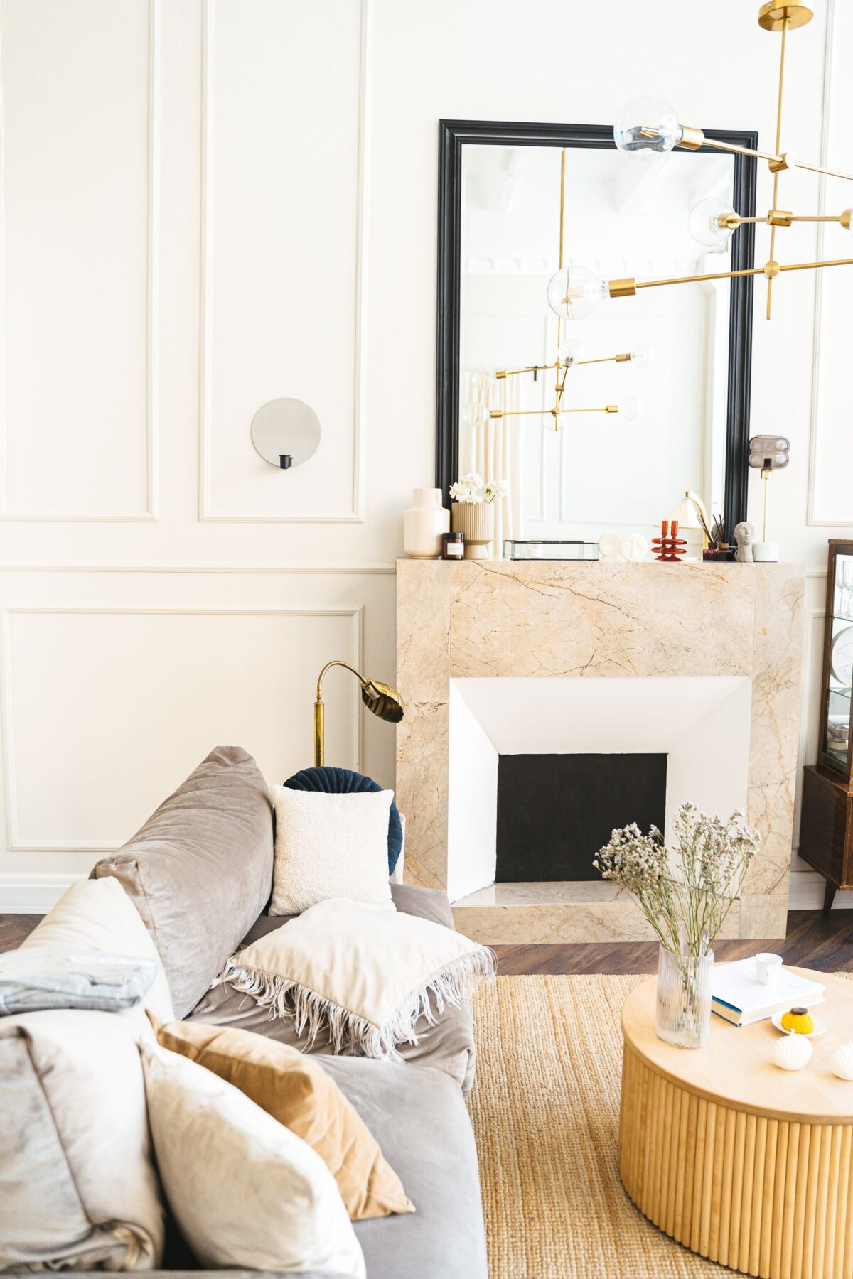 Cheminée en marbre beige dans un salon aux murs blancs moulurés