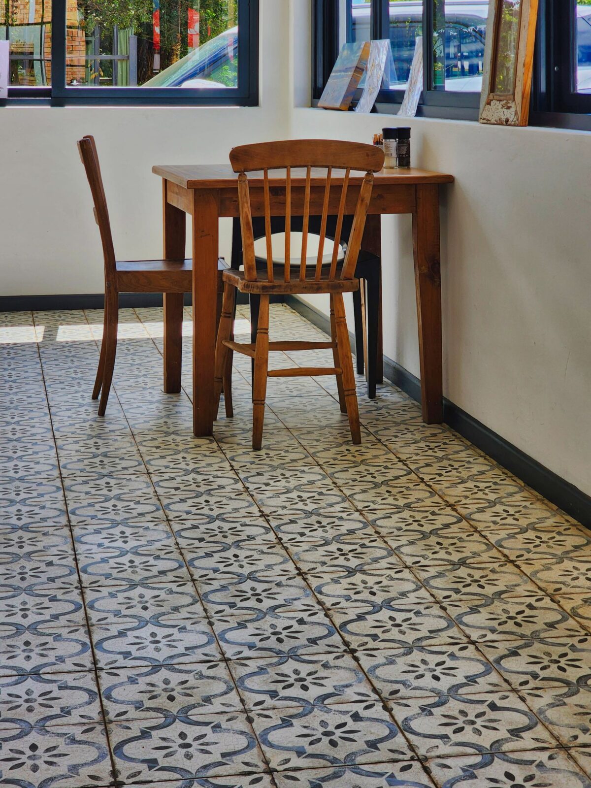 Coin repas avec des chaises en bois sur un sol en carreaux de ciment à motif floral