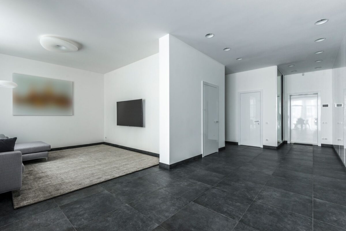 Couloir avec un sol en carrelage gris foncé grand format et rangements muraux blancs