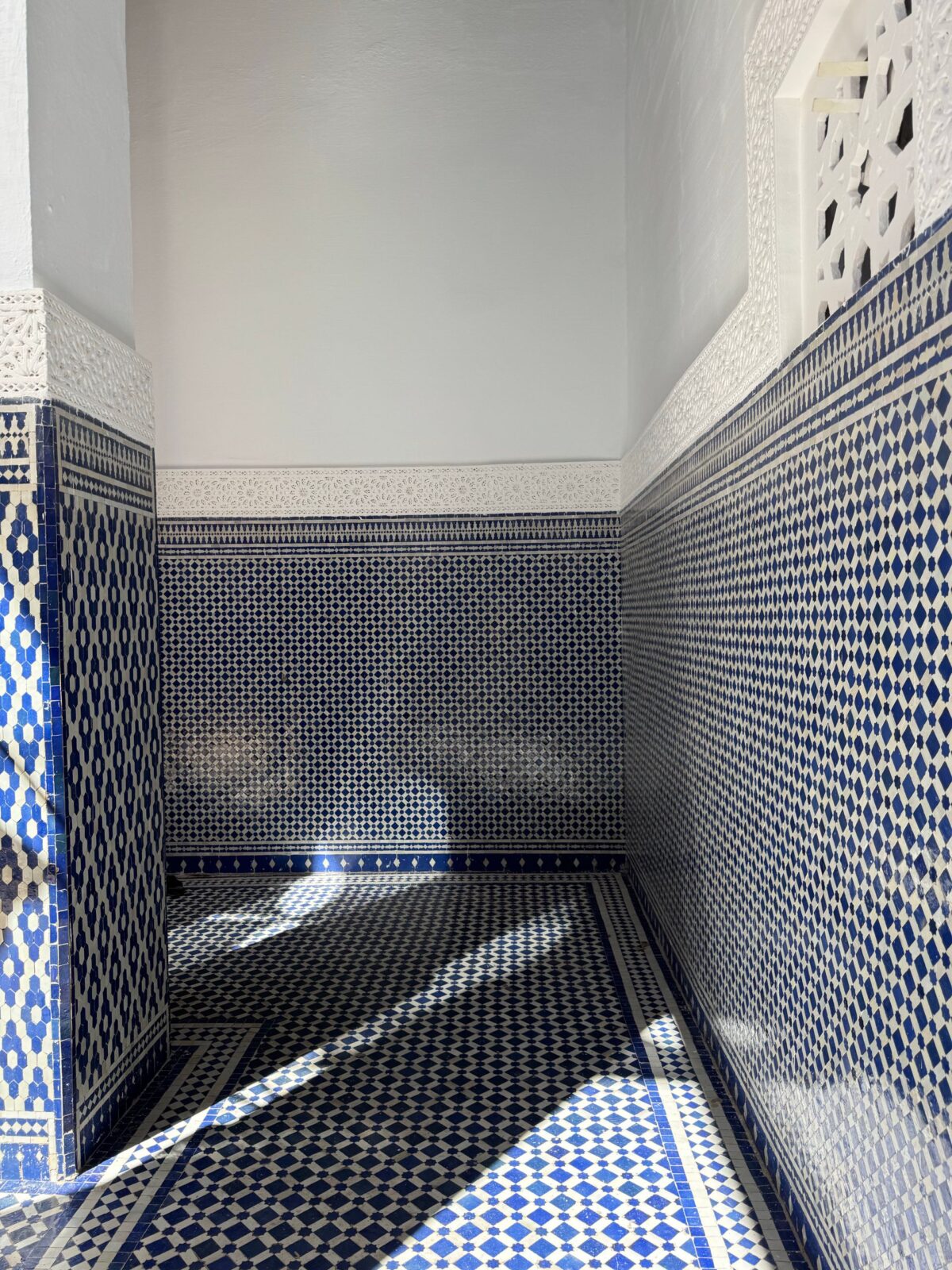 Couloir marocain au sol en damier noir et blanc et murs en mosaïque bleue