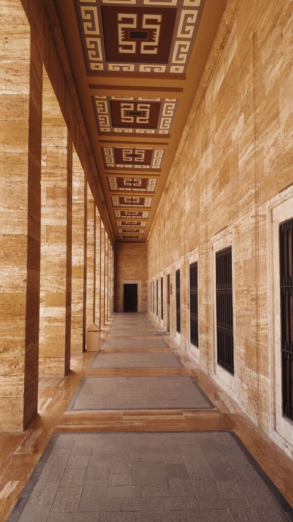 Couloir voûté au sol et aux murs en pierre beige, éclairé en enfilade
