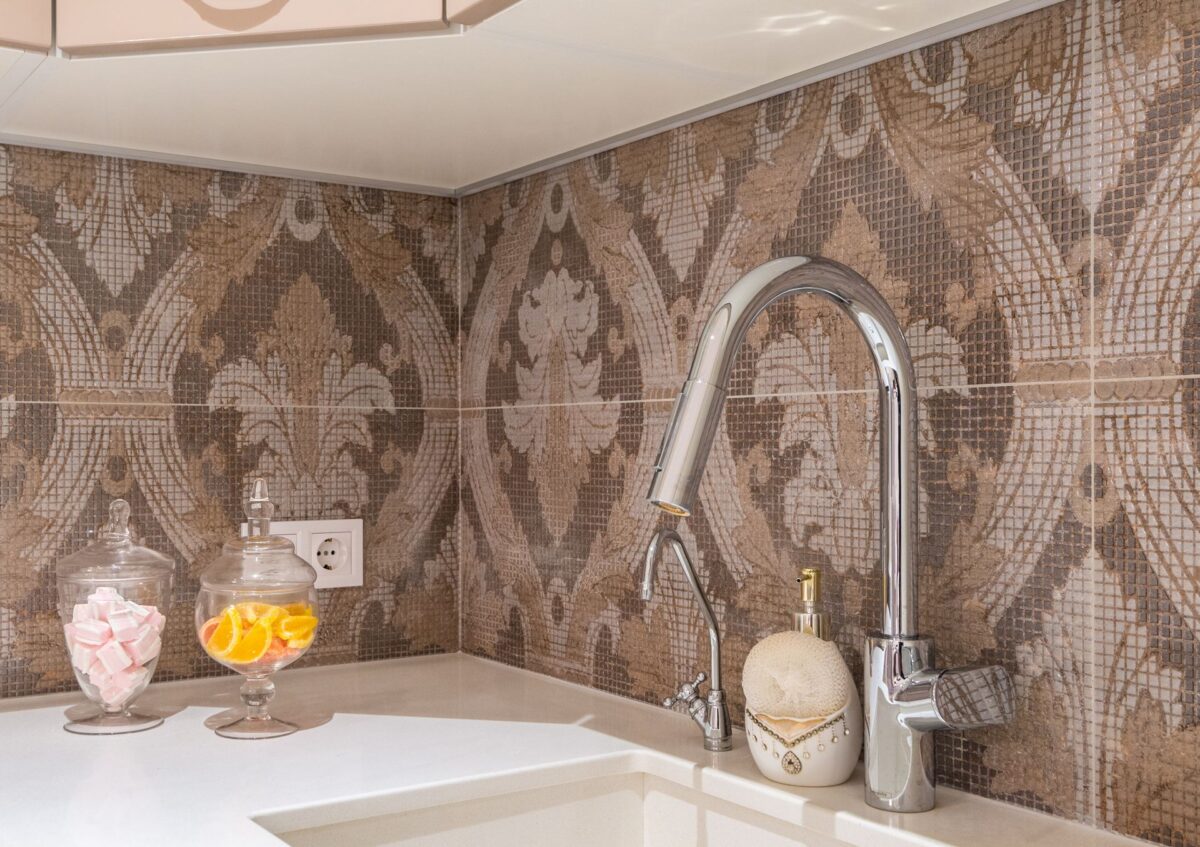 Crédence de cuisine en carreaux de faïence à motifs ornementaux marron et beige, robinet chromé et évier