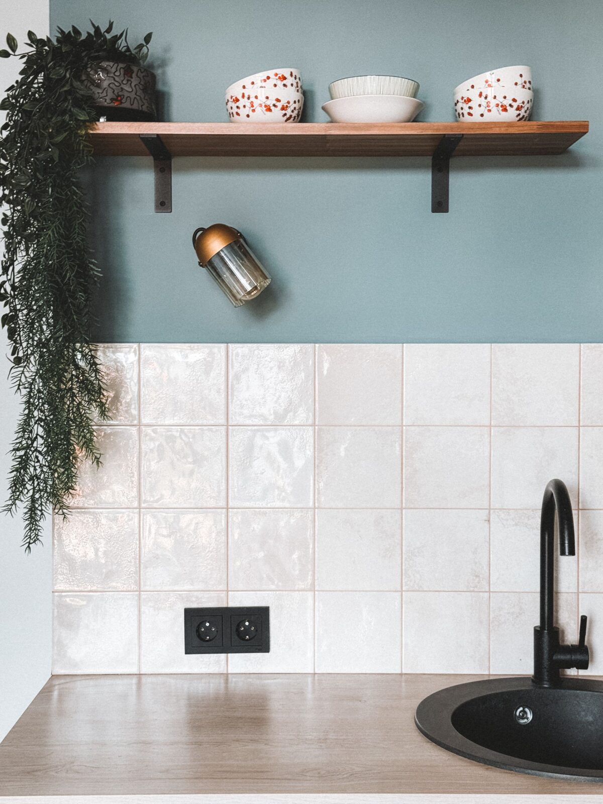 Crédence de cuisine en carreaux blancs artisanaux avec robinet noir et étagère en bois