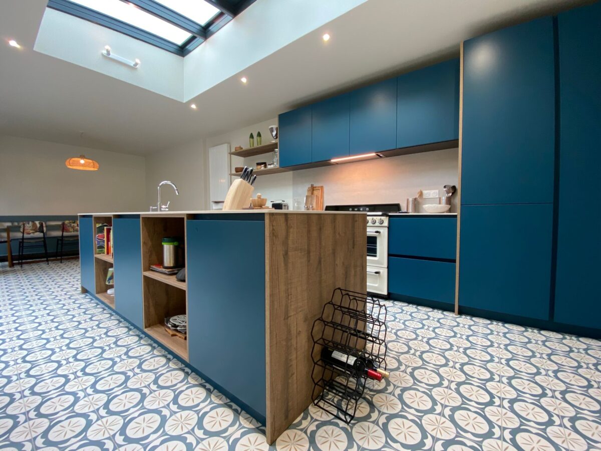 Cuisine ouverte aux meubles bleus avec un sol en carreaux de ciment à motifs bleu et blanc