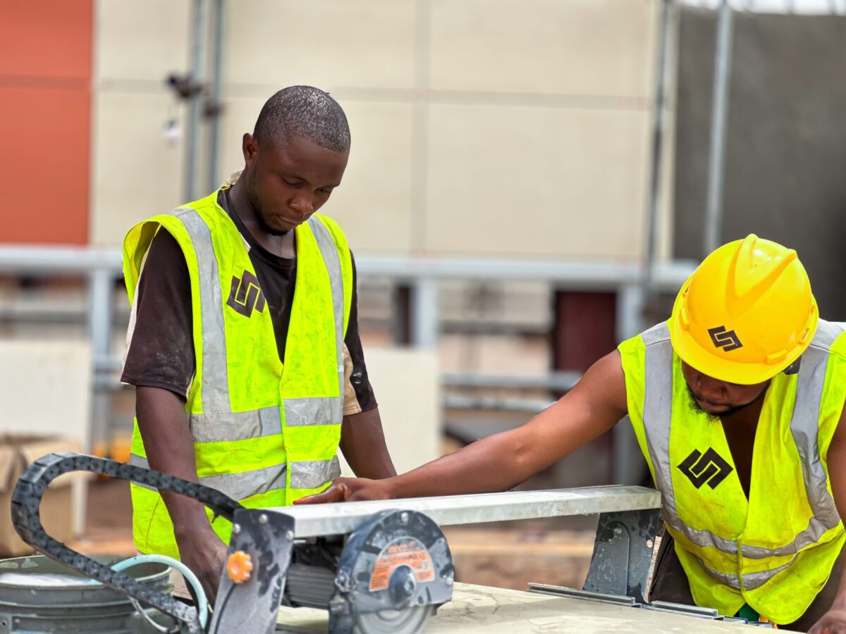 Deux ouvriers en gilet de sécurité découpant une grande dalle sur une scie de chantier
