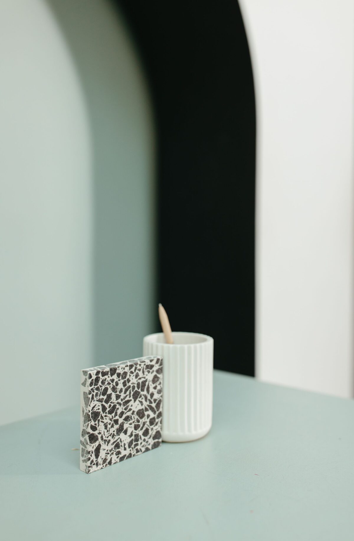 Échantillon de carreau de terrazzo gris posé sur une tablette à côté d'une bougie