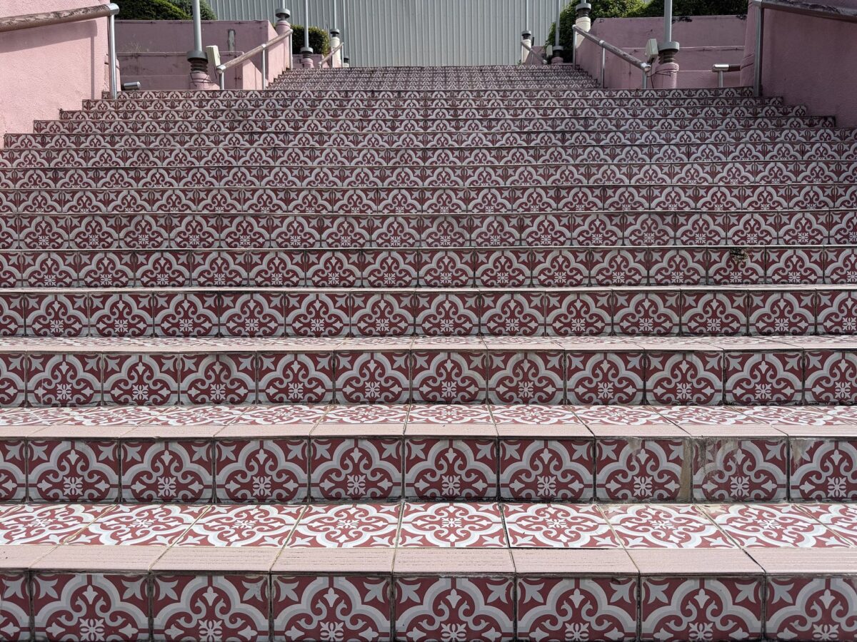 Escalier ancien habillé de carreaux de ciment à motif floral rose et gris
